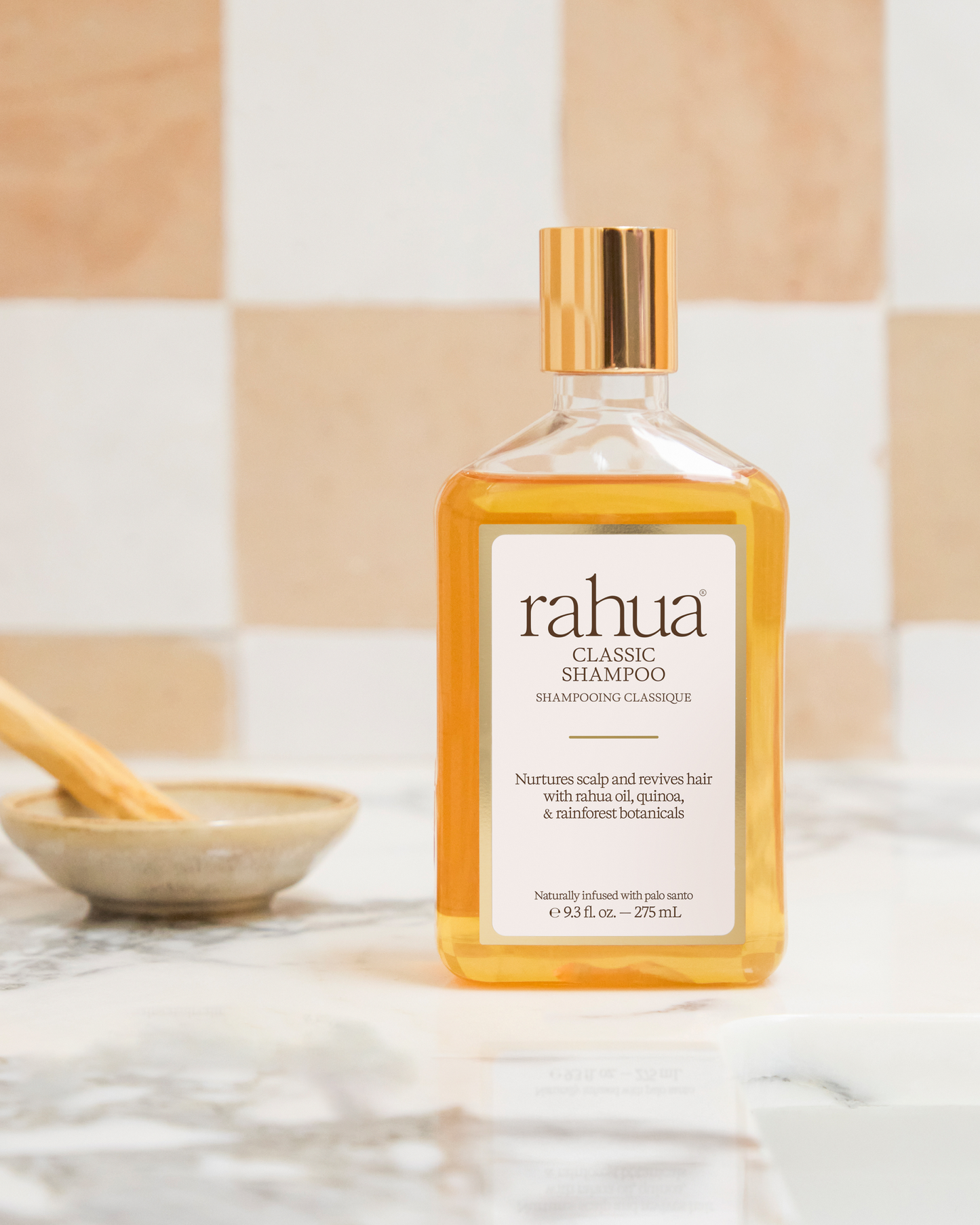 Rahua shampoo bottle on a marble surface with a neutral tile background|variant:93-oz