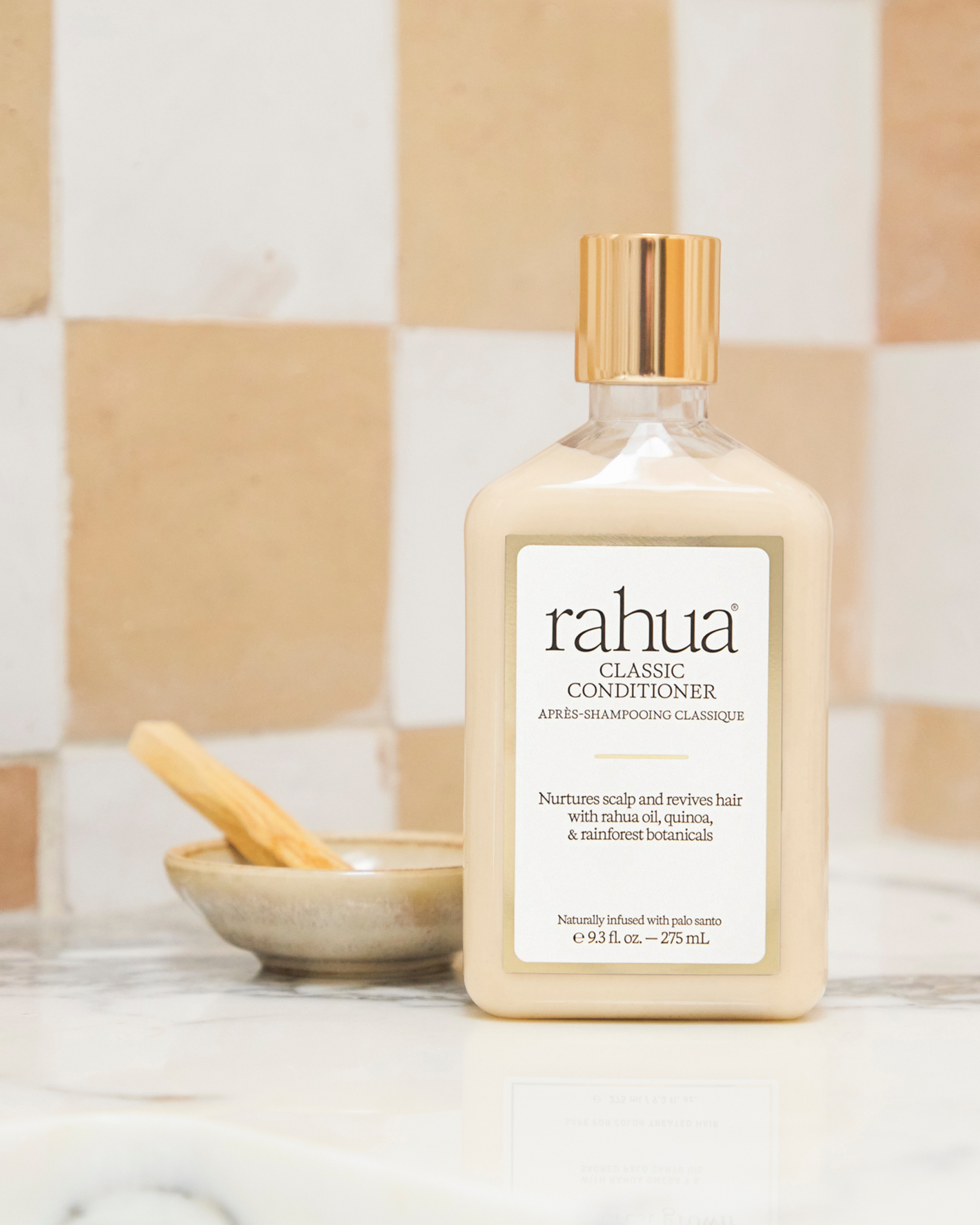 Bottle of rahua classic conditioner on a bathroom counter with a checkered tile background|variant:18-oz