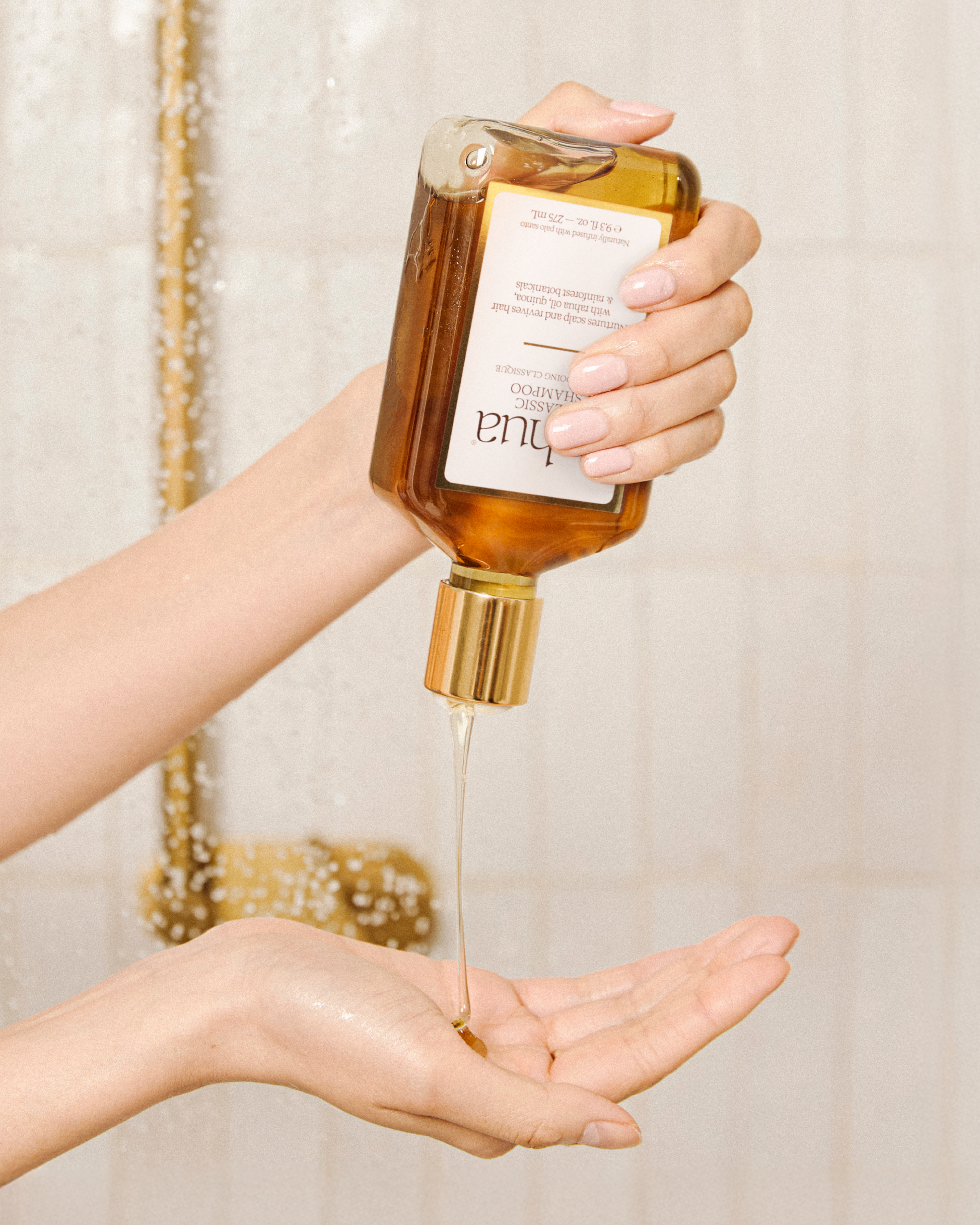 Hand holding a bottle of Tula skincare product with dropper over another hand.|variant:18-oz