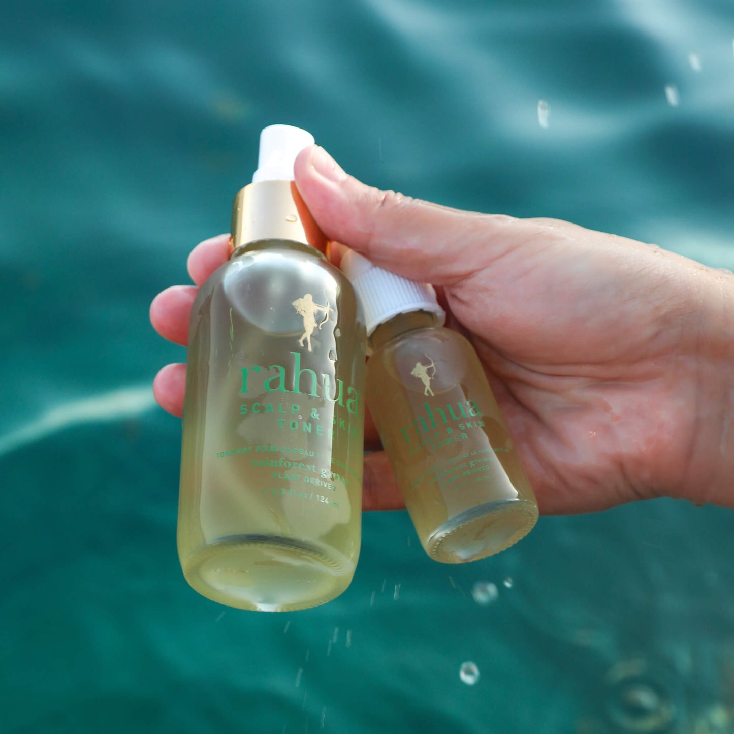 4.2 oz glass spray bottle with a gold collar  with a smaller glass spray bottle and green text rahua scalp and skin toner model holding over the ocean 2 oz travel friendly tsa safe|variant:1-oz