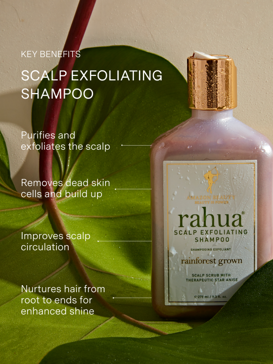 bottle of rahua scalp exfoliating shampoo sitting on a leaf with key benefits listed including purifying, exfoliating, removing build up, improving scalp circulation and nourishment|variant:074-oz